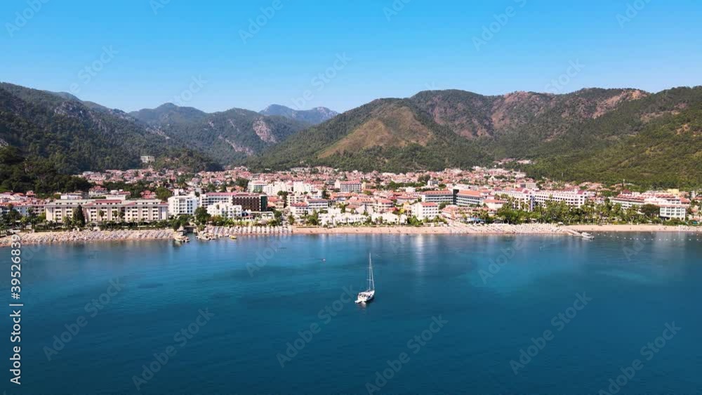 Drone flight over the resort town and hotels against the backdrop of the Mediterranean blue sky of the beach and bay with yachts and pier and mountains. Turkey. Drone flight over the resort town and hotels against the backdrop of the Mediterranean blue sky of the beach and bay with yachts and pier and mountains. Turkey.