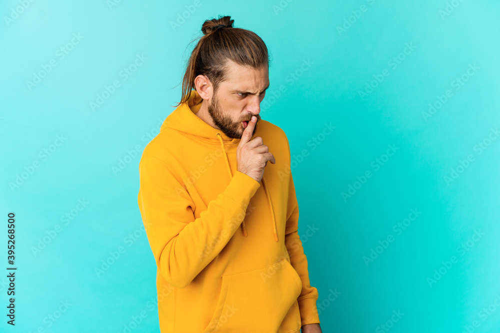 Young man with long hair look keeping a secret or asking for silence.