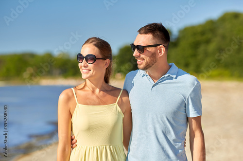leisure, relationships and people concept - happy couple in sunglasses hugging on summer beach