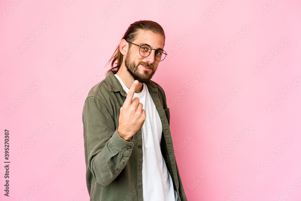 Young man with long hair look pointing with finger at you as if inviting come closer. Young man with long hair look pointing with finger at you as if inviting come closer.