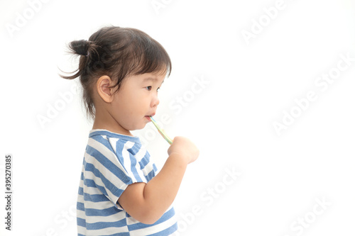 A cute little Asian girl brushing her teeth isolated on white background. Healthy teeth concept.