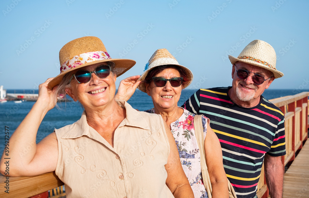 Funny expressions and smiles for a group of senior people looking at camera enjoying sea excursion. Active lifestyle for three retired people