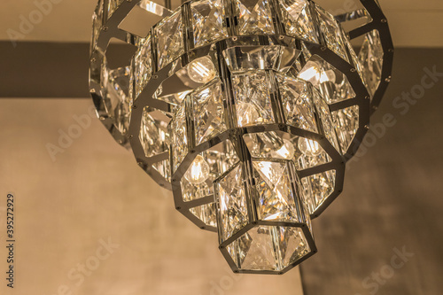 Close-up of the glowing expensive chandelier from a crystal ceiling lampshade. Classic style in a modern interior. Inside. Warm light.