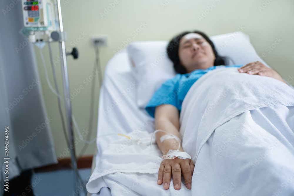 Close-up of a patient's hand, an Asian woman lying on a bed, giving a saline solution at a hospital Close-up of a patient's hand, an Asian woman lying on a bed, giving a saline solution at a hospital