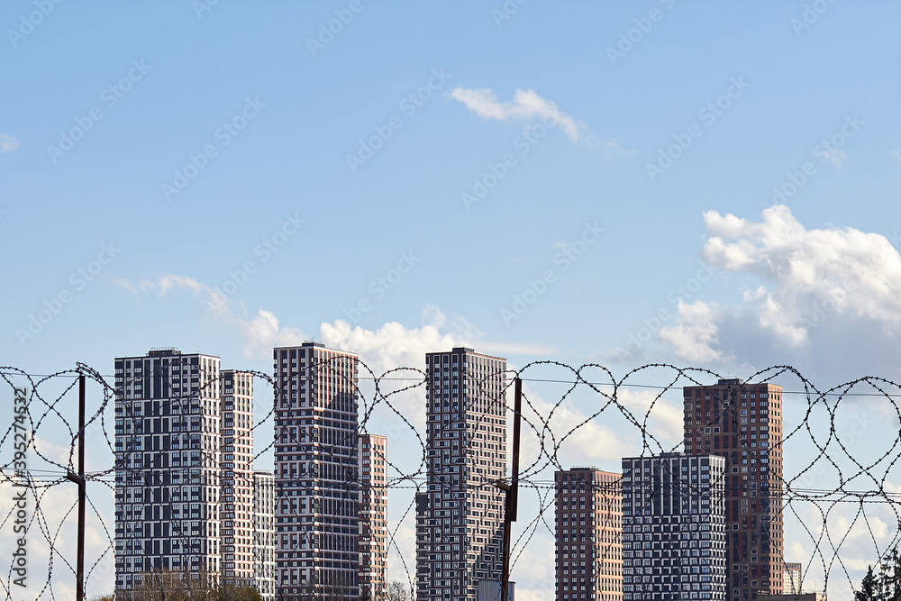 City is isolated behind the bars of barbed wire, the house and the sky behind a fence with barbed wire City is isolated behind the bars of barbed wire, the house and the sky behind a fence with barbed wire