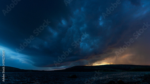 View of a thundercloud over the sea. Panorama, landscape with a dramatic sky before sunset. Tinted with little noise and a film defect. hdr image.
