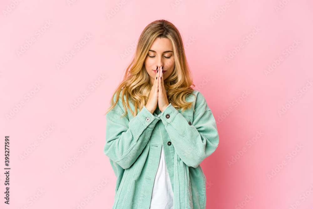 Young caucasian blonde woman holding hands in pray near mouth, feels confident. Young caucasian blonde woman holding hands in pray near mouth, feels confident.