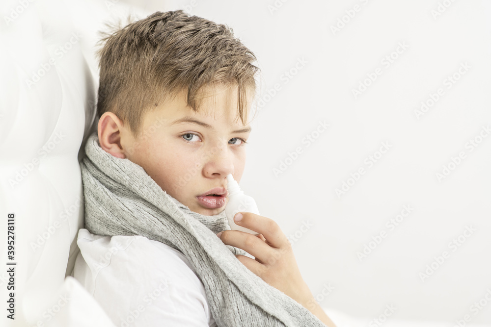 Sick teen boy washing his nose with medicine while sitting on bed at home Sick teen boy washing his nose with medicine while sitting on bed at home
