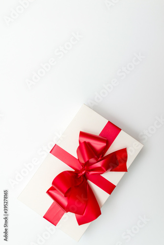 Top view Cristmas white gift box present red bow white background.
