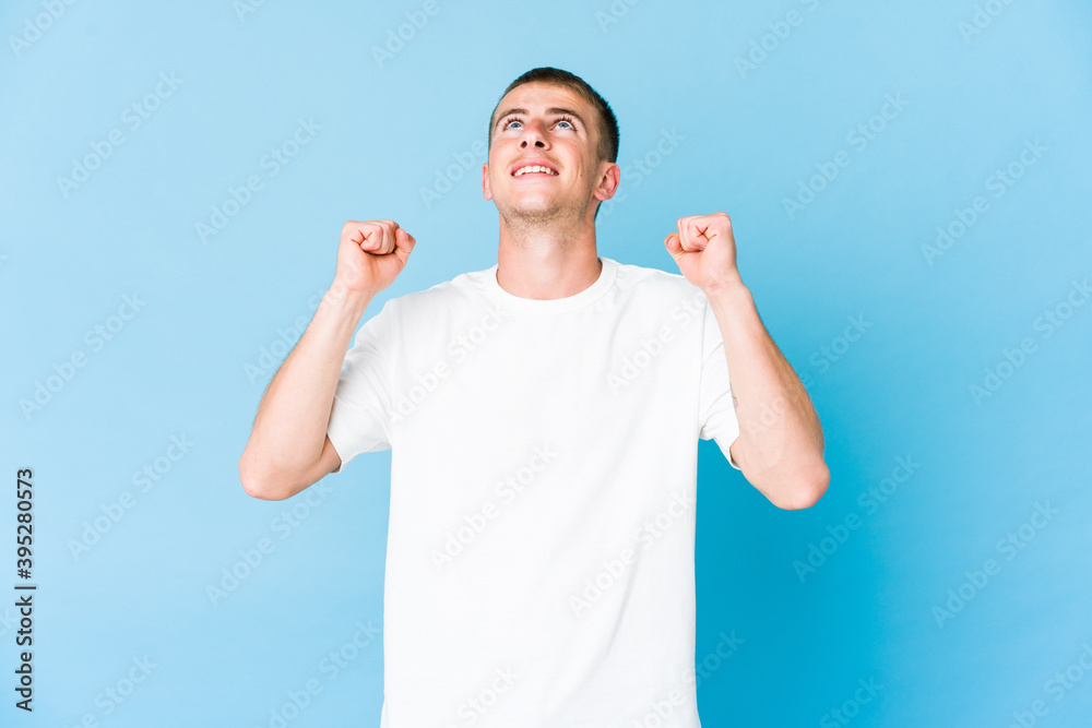 Young caucasian handsome man celebrating a victory, passion and enthusiasm, happy expression.