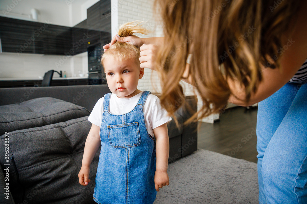 Mother makes her little daughter's hair. Hair care from an early age. Mother makes her little daughter's hair. Hair care from an early age.