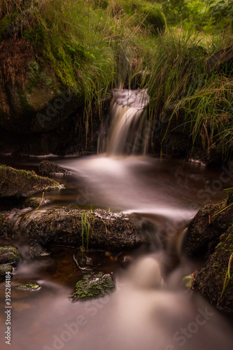 Small waterfall and pool on a stream flowing down Pendle hill in lancashire. Smooth water and green vegetation.