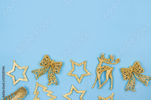 Christmas or New Year composition - golden decorations on pastel blue background. Festive frame with copyspace for your text. Selective focus