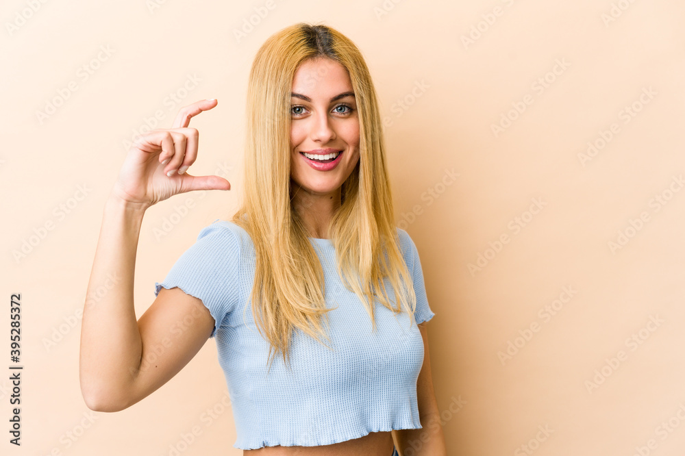 Young blonde caucasian woman holding something little with forefingers, smiling and confident. Young blonde caucasian woman holding something little with forefingers, smiling and confident.