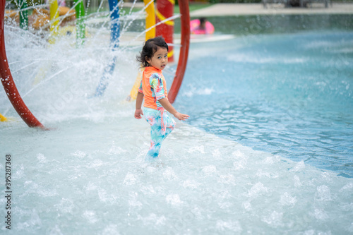 Little girl in swimming suit playing at waterpark.