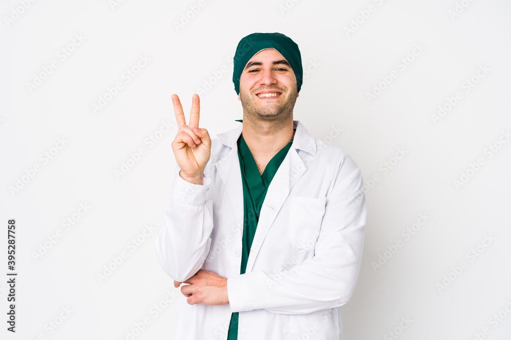 Young surgeon man isolated on white background showing number two with fingers. Young surgeon man isolated on white background showing number two with fingers.