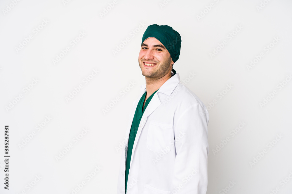Young surgeon man isolated on white background looks aside smiling, cheerful and pleasant. Young surgeon man isolated on white background looks aside smiling, cheerful and pleasant.