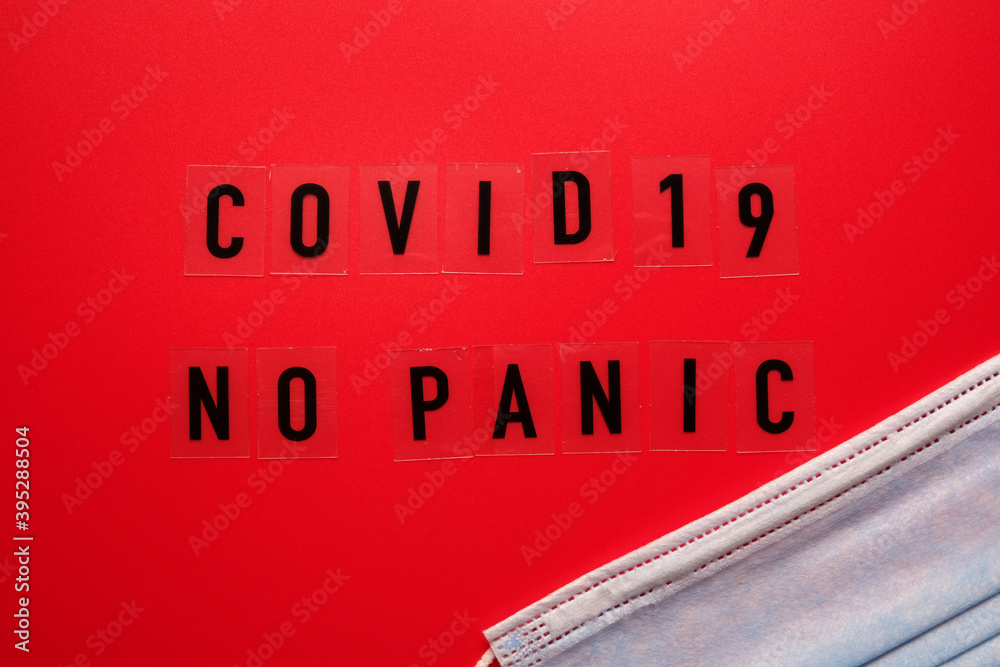 Obraz premium Words covid 19 no panic on a red background and a medical mask.