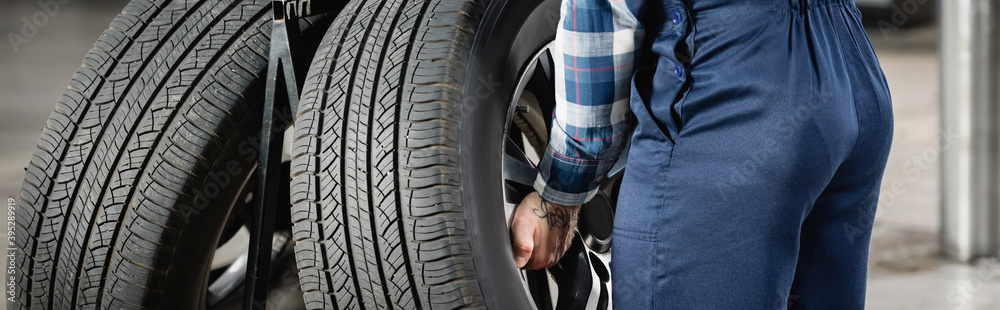partial view of repairman taking car wheel in workshop, partial view of repairman taking car wheel in workshop,