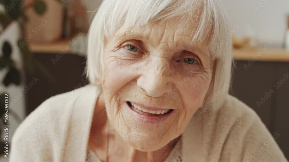 Close up portrait of positive senior woman looking at camera and smiling while posing at home Close up portrait of positive senior woman looking at camera and smiling while posing at home