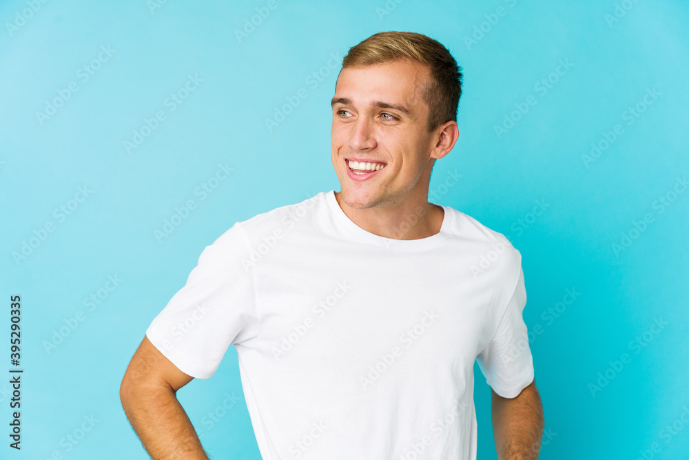 Young caucasian handsome man laughs happily and has fun keeping hands on stomach.