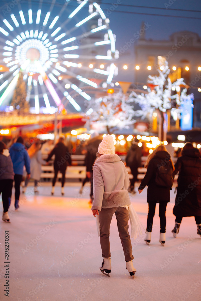 Φωτογραφία Young  woman ice skating on the ice arena in the city square in winter on Christmas Eve