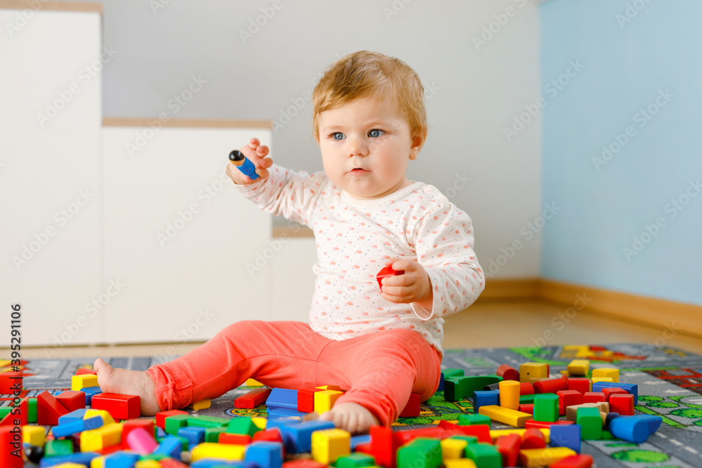Adorable baby girl playing with educational toys . Happy healthy child having fun with colorful different wooden blocks at home in domestic room. Baby learning colors and forms Adorable baby girl playing with educational toys . Happy healthy child having fun with colorful different wooden blocks at home in domestic room. Baby learning colors and forms