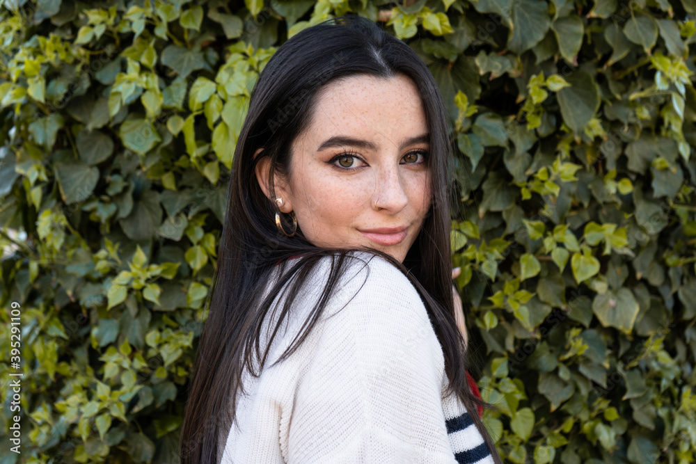 Portrait of a very pretty young woman with black hair and freckles looking at the camera Portrait of a very pretty young woman with black hair and freckles looking at the camera