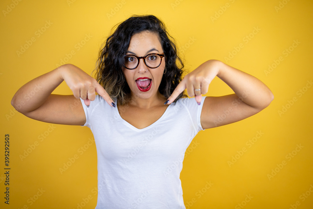 Young beautiful woman wearing casual white t-shirt over isolated yellow background looking confident with smile on face, pointing oneself with fingers proud and happy. Young beautiful woman wearing casual white t-shirt over isolated yellow background looking confident with smile on face, pointing oneself with fingers proud and happy.