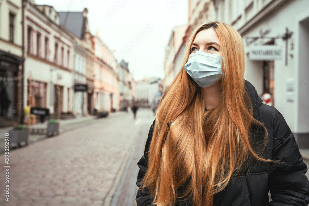 Portrait of girl in protective mask on city street. Beautiful young woman with long hair outdoors. Quarantine coronavirus Portrait of girl in protective mask on city street. Beautiful young woman with long hair outdoors. Quarantine coronavirus