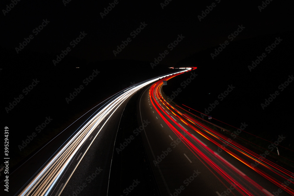 Cars light trails on a curved highway at night. Night traffic trails