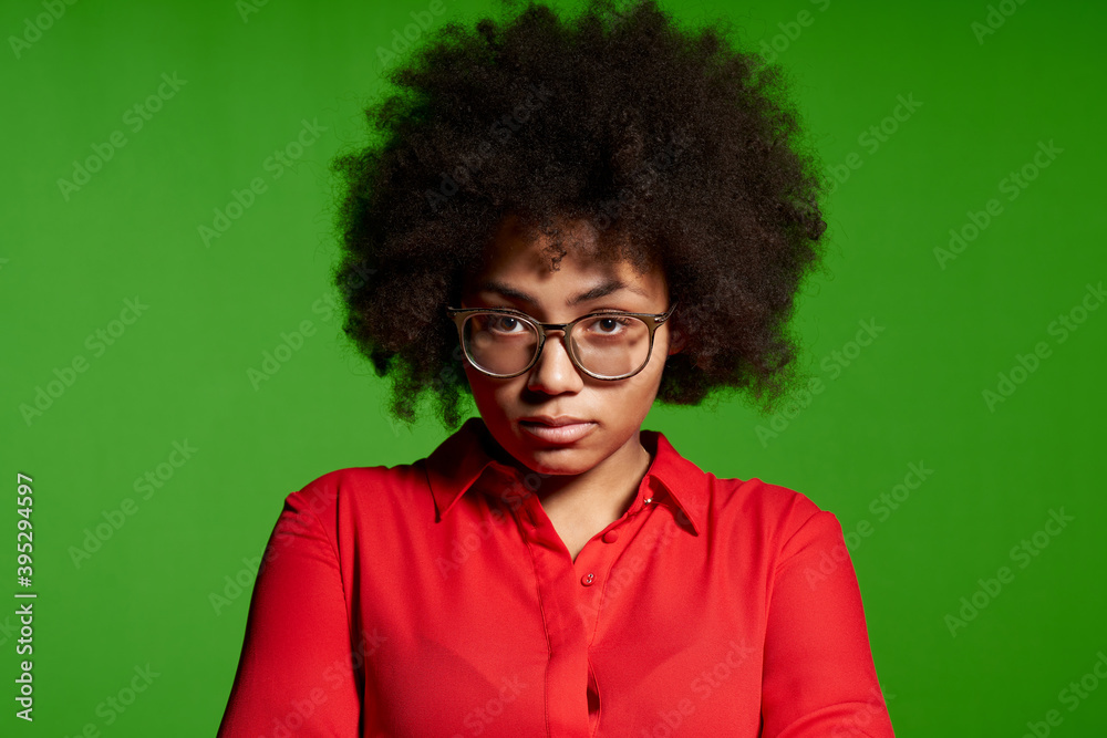 Discontent serious young African-American girl in glasses and red shirt Discontent serious young African-American girl in glasses and red shirt