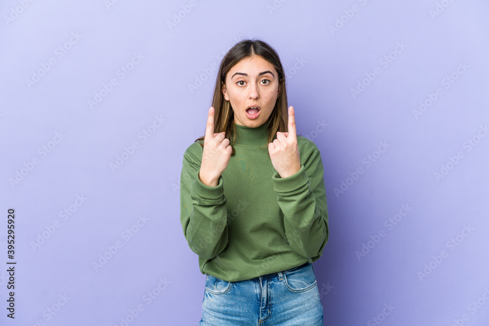 Young caucasian woman pointing upside with opened mouth. Young caucasian woman pointing upside with opened mouth.