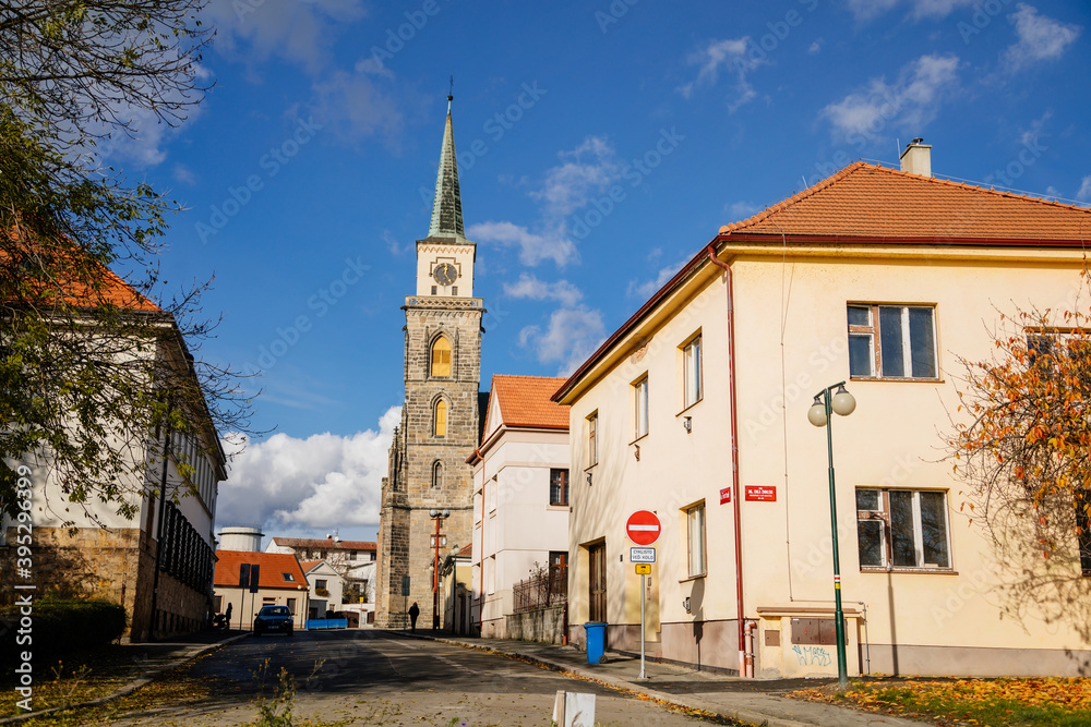 Medieval catholic old church of Saint Jilji with gothic high clock tower in sunny autumn day, street view, Nymburk, Central Bohemia, Czech Republic