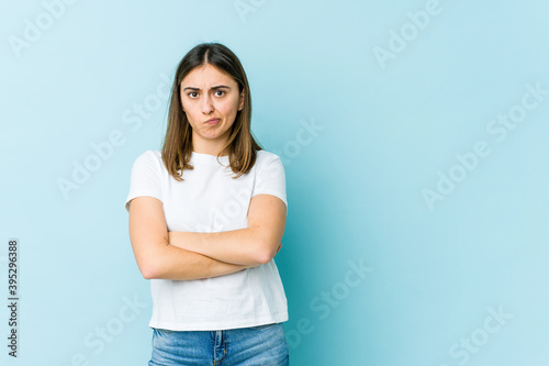 Young caucasian woman frowning face in displeasure, keeps arms folded.