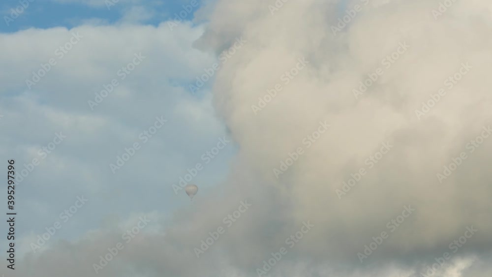 A hot air balloon flying high and dives into a cloud. A hot air balloon flying high and dives into a cloud.