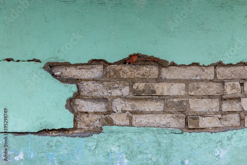 Aged white brick wall with a crack. Grunge style. Creative photo for the designer. Green background. Copy space. plaster , the problem of major repairs of houses