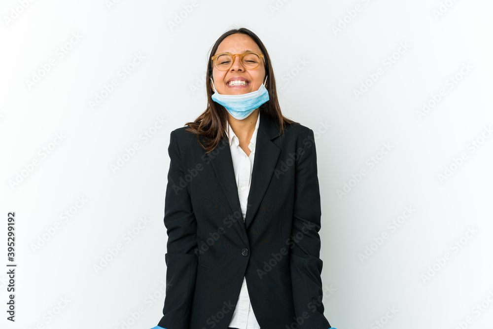 Young business latin woman wearing a mask to protect from covid isolated on white background laughs and closes eyes, feels relaxed and happy.