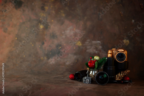 christmas and new year background for photographer. christmas set gold camera and lenses and christmas tree toys on dark background horizontal orientation