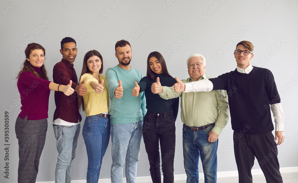 Obraz premium Group of happy diverse people standing together, giving thumbs-up and looking at camera