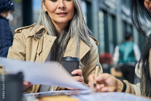 Beautiful woman studying documents with colleague outdoors