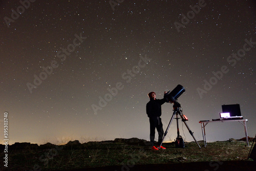 Fényképezés Young woman fond of astronomy observing through her telescope