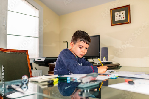 Concentrated child doing homework in daddy's office