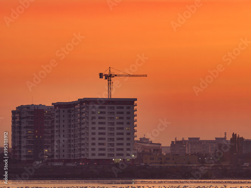 Beautiful sunset over Lake Dâmbovița (Lacul Morii) in Bucharest, Romania. Sunset over a lake with a construction crane in the background.