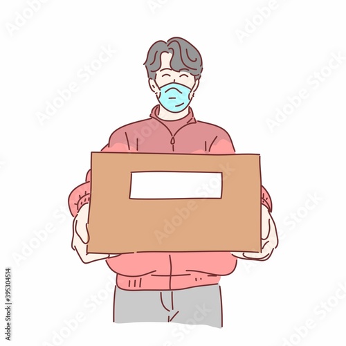 Delivery man wearing medical mask holding box.