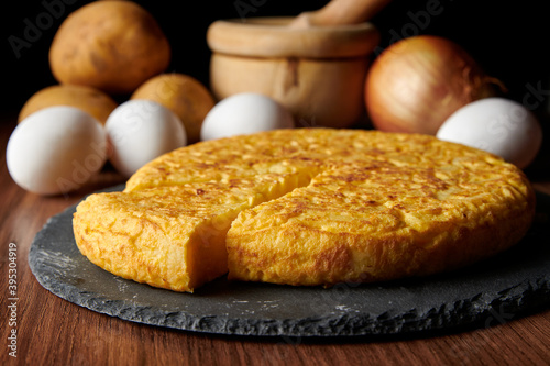 A closeup of a fresh tasty Spanish omelette and the ingredients on the background, a traditional dish from Spain