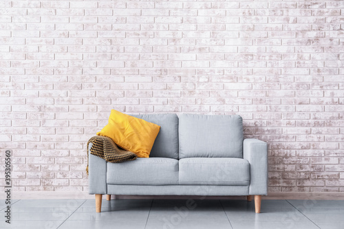 Stylish sofa near brick wall in room