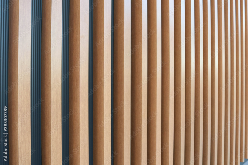 Wooden vertical slats batten on a light gray wall background. Interior detail, texture, background. The concept of minimalism and Scandinavian style in the interior. Copy space