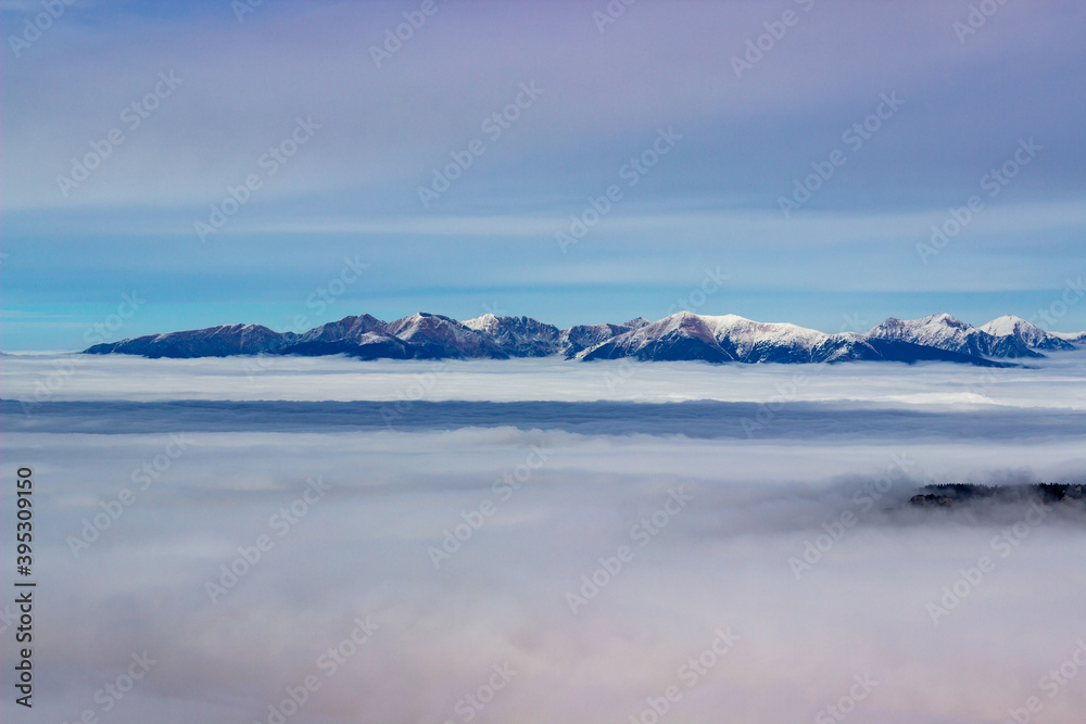 Sun is shining at foggy autumn day on top of the low Tatry looking into mountain tops of the high Tatry in distance