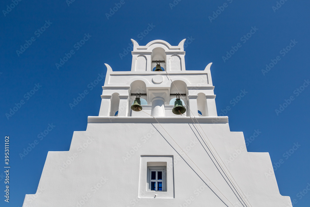White church with blue dome and bell in Santorini